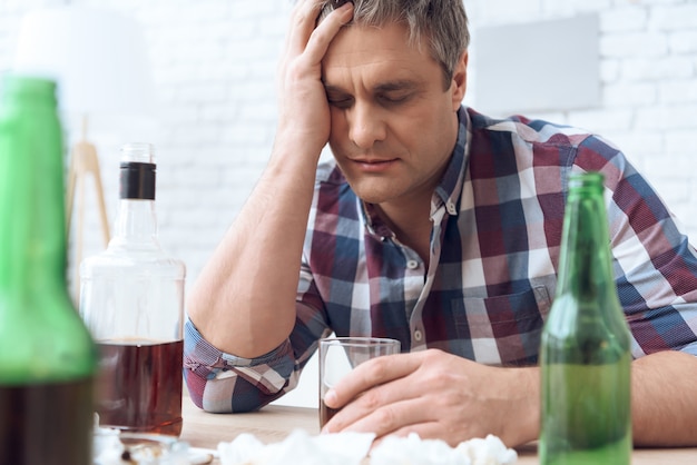 Drunk father is sitting at table with glass