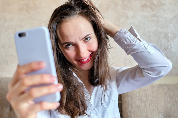 Drunk girl with smeared lipstick makes selfie photo.