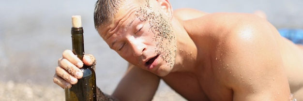 Drunk man with bottle of wine lies on beach alcoholic drinks\
and vacation at sea concept