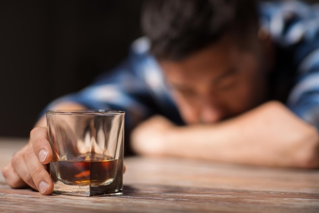 drunk man with glass of alcohol on table at night