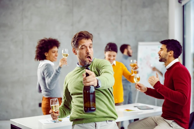 A drunk and tipsy businessman standing in his office and celebrating success