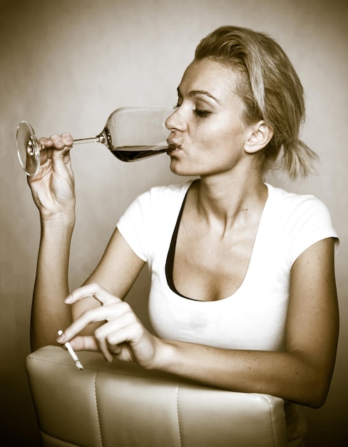 Drunk woman drinking wine and smoking cigarette