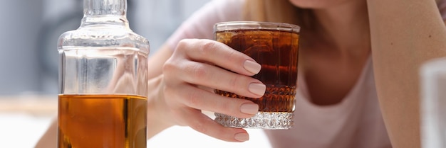 Drunk woman holding glass of whiskey and alcoholics alone