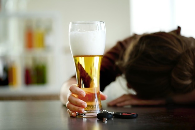 Foto donna ubriaca seduta al tavolo con la birra e il primo piano delle chiavi dell'auto non bere e guidare il concetto