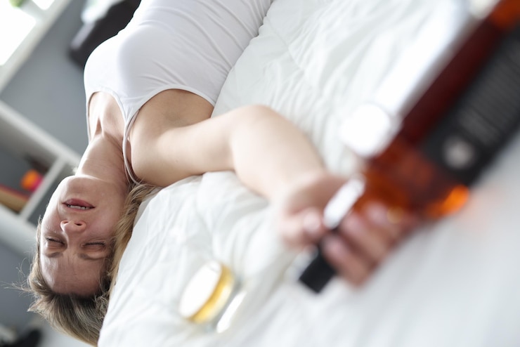 Photo drunk woman sleeping with bottle of alcohol in bed closeup