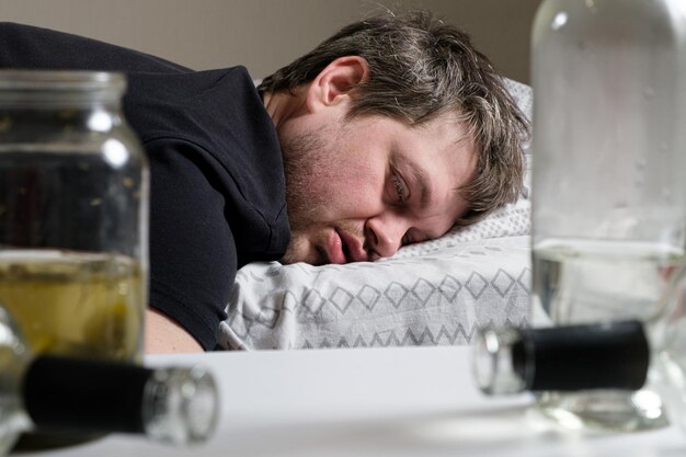 A drunken alcoholic man lies on the bed