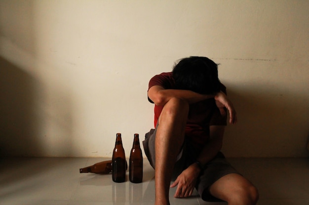 Drunken man with beer bottle are having stress in life and\
sitting alone in a empty room, sad ,lonely ,chool, adolescence,\
home violence, unwanted love problems, alone, family