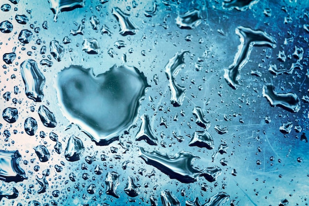Druppel in de vorm van een hart op blauw nat glas