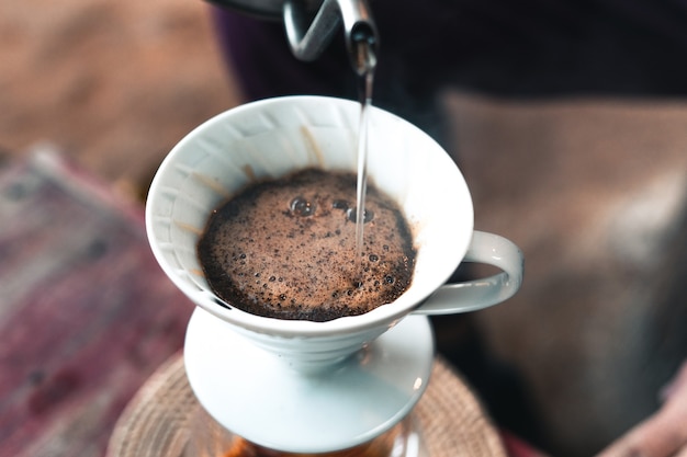 Druppel koffie, barista giet water op koffiemalen met filter, koffie zetten