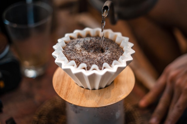 Druppel koffiebarista die water op koffiedik giet met filter