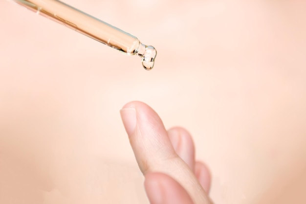 Druppelbuis druppel water of serum op vinger Cosmetische pipet met druppels olie Conceptuele huidverzorging en schoonheid