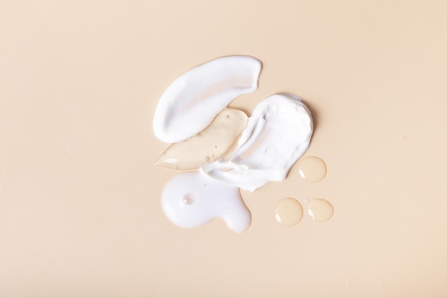 Druppels en uitstrijkjes van cosmetica bovenaanzicht op beige achtergrond