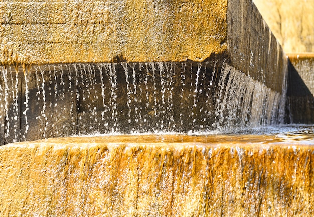 Druppels koud water rennen in de zomer over de stenen in de fontein