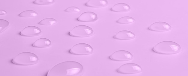 Druppels micellair water of cosmetische tonic op een roze achtergrond Close-up macrofotografie