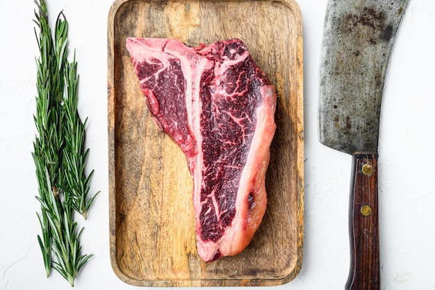 Dry aged Raw T bone or porterhouse marbled beef meat Steak with herbs and spices set, on white stone table, top view flat lay