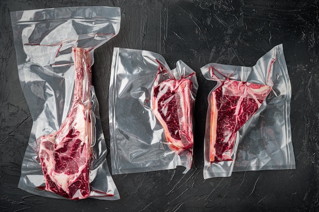 Dry aged vacuum steak  set, tomahawk, t bone and club steak cuts, on black stone table, top view flat lay