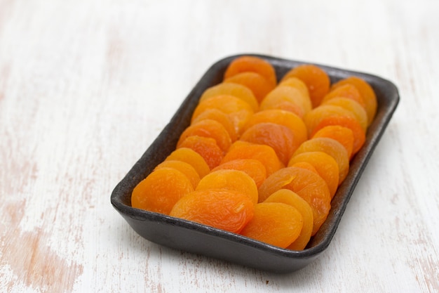 Dry apricot on black plastic dish