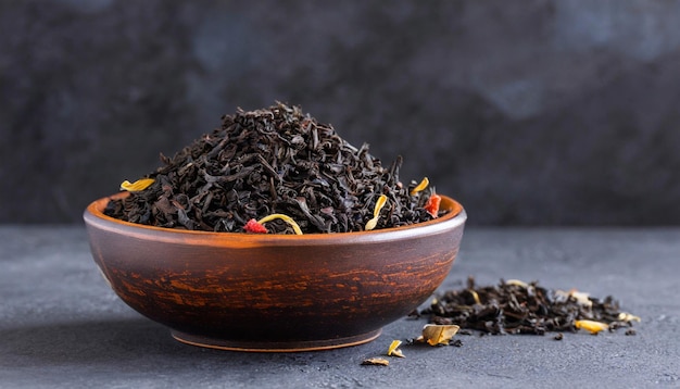 Dry black tea in ceramic bowl on a dark