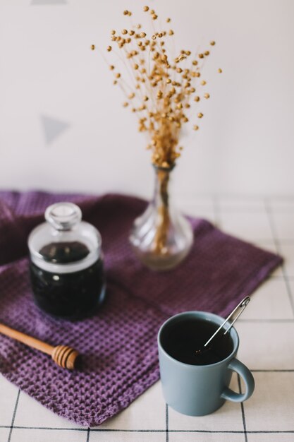 Сухой черный чай в стеклянной банке и медовое веретено на кухонном фоне, горячий напиток в холодный период