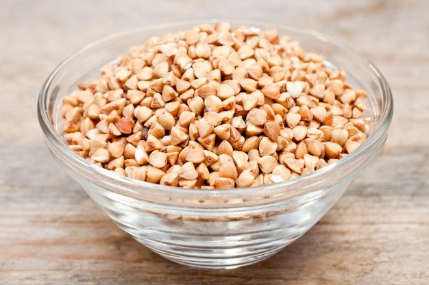 Dry buckwheat groats in a bowl on wooden table