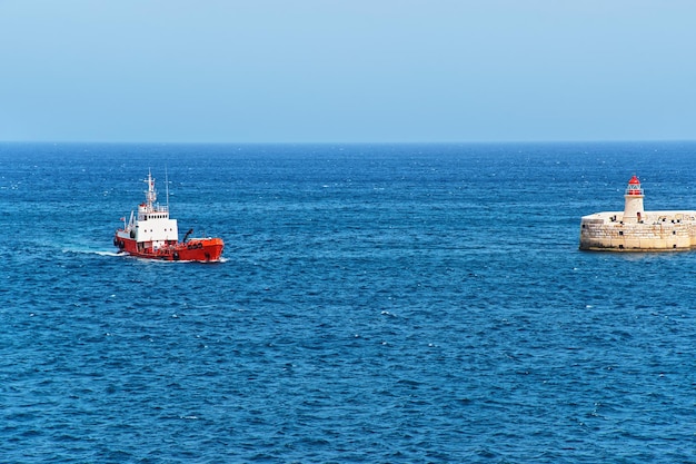 Dry cargo carrier at breakwater at fort ricasoli of kalkara at grand harbor in valletta, malta