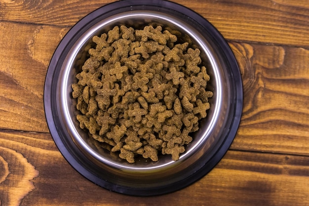 Dry cat food in bowl on wooden background Pet food on wood surface Top view