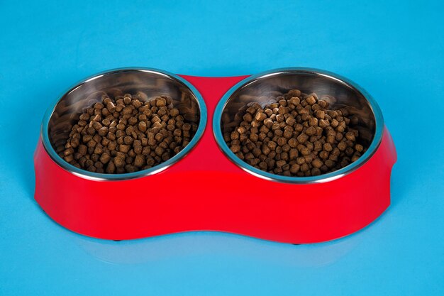 Dry cat food in bowls isolated on blue background