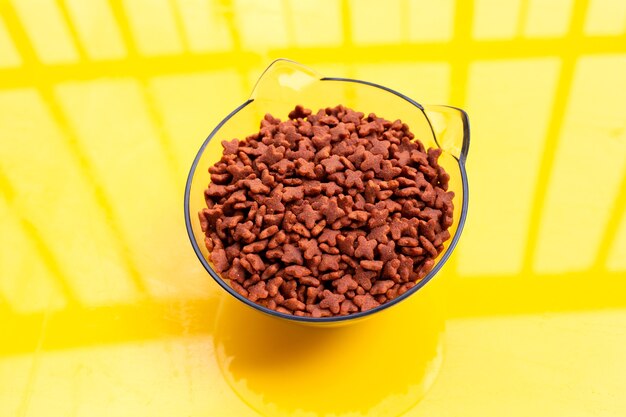 Dry cat food isolated on yellow background. Copy space