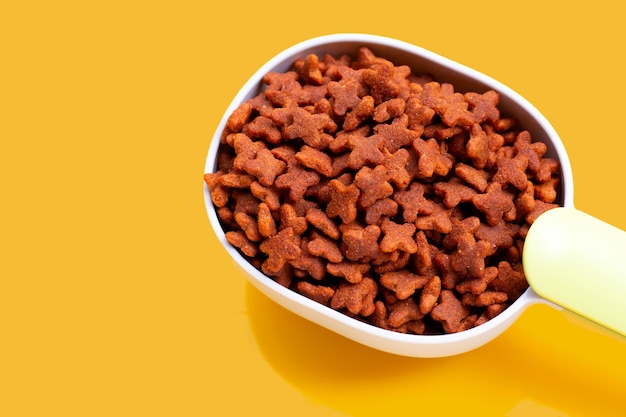 Dry cat food isolated on yellow background. copy space