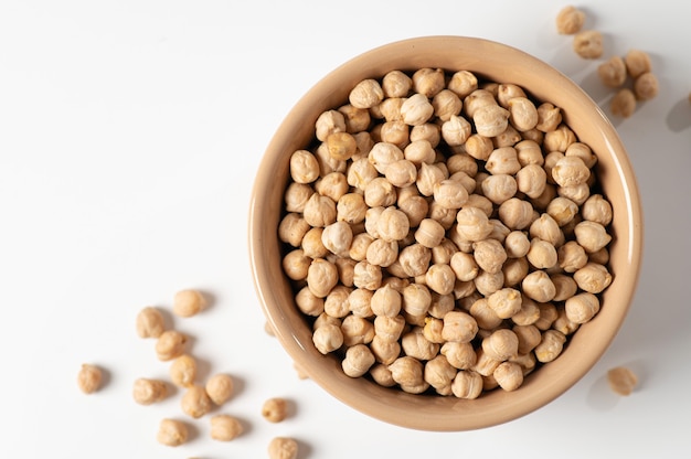 Photo dry chickpeas, in a ceramic dish on a white table, top view, close-up