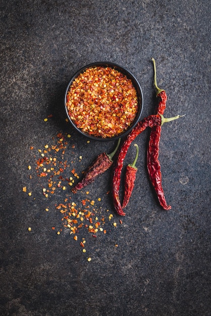 Dry chili pepper flakes Crushed red peppers on the black table Top view