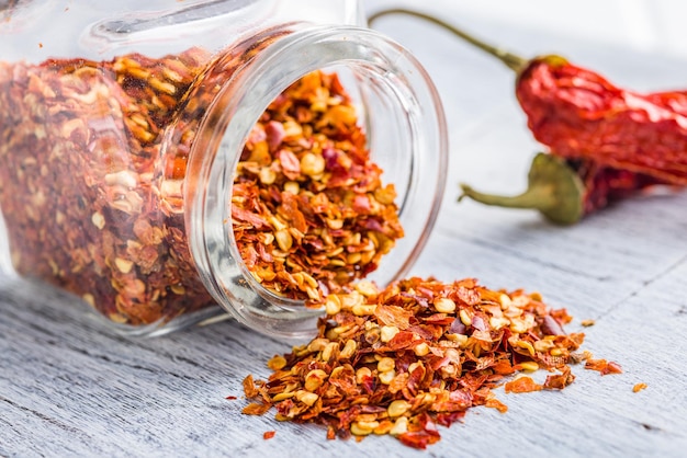 Dry chili pepper flakes Crushed red peppers in jar on the white table