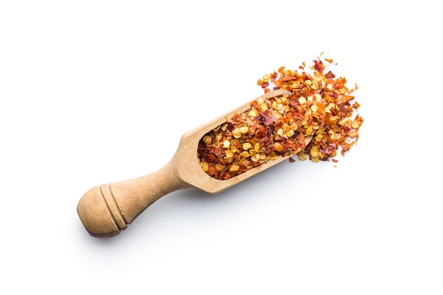 Dry chili pepper flakes in wooden scoop Crushed red peppers isolated on the white background