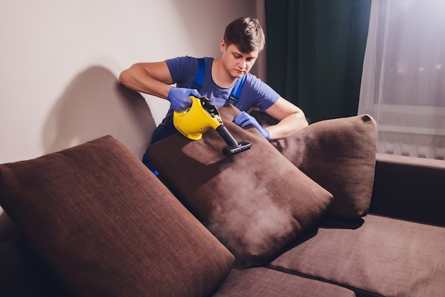 Dry cleaner's employee removing dirt from furniture in flat, closeup.