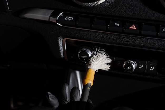 車のダッシュボードのブラシを使ったドライ クリーニング オートディテーリング サービス 自動車のブラック レザー インテリアの個々の要素のクリーニング