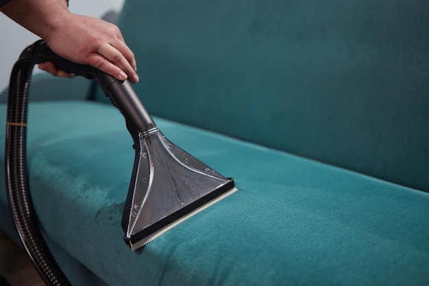 Dry cleaning worker removing dirt from sofa indoors