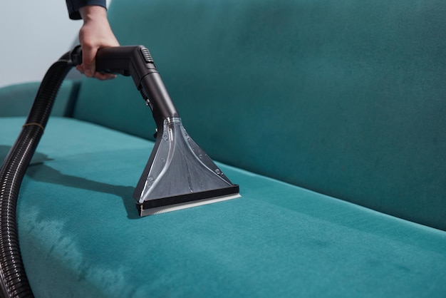 Dry cleaning worker removing dirt from sofa indoors