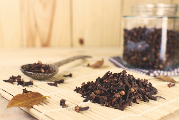 Photo dry clove and dry clove spoon with dry clove bottle on wooden background