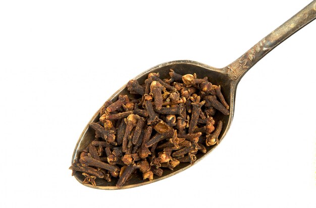 dry cloves in a spoon on a white background. 