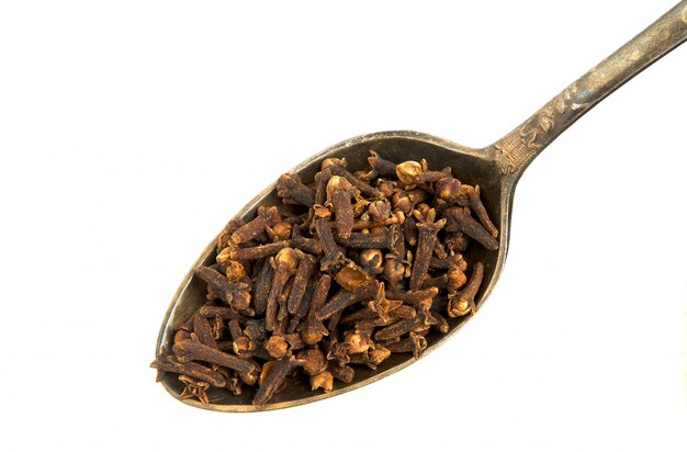 Photo dry cloves in a spoon on a white background.