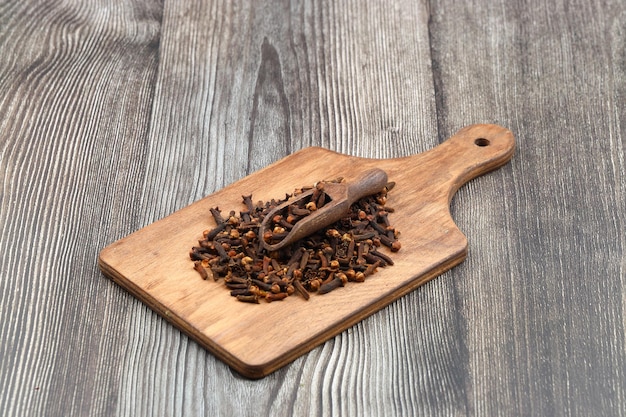 Dry cloves in wooden scoop isolated on wooden background with clipping path Top view Flat lay selective focus