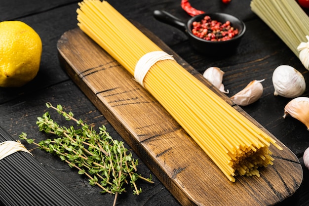 Dry colorful pasta spaghetti set, on black wooden table background