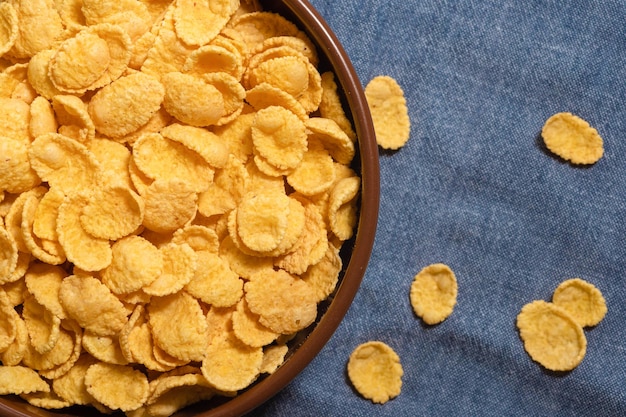 Dry corn flakes in a bowl closeup top view