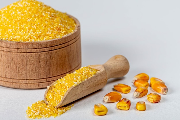 Dry corn grits in a wooden bowl and scoop with whole grains of corn