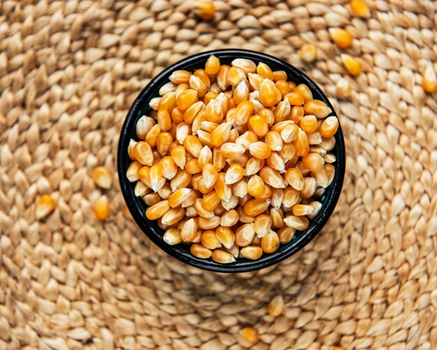 Dry Corn seeds in  bowl on straw mat background