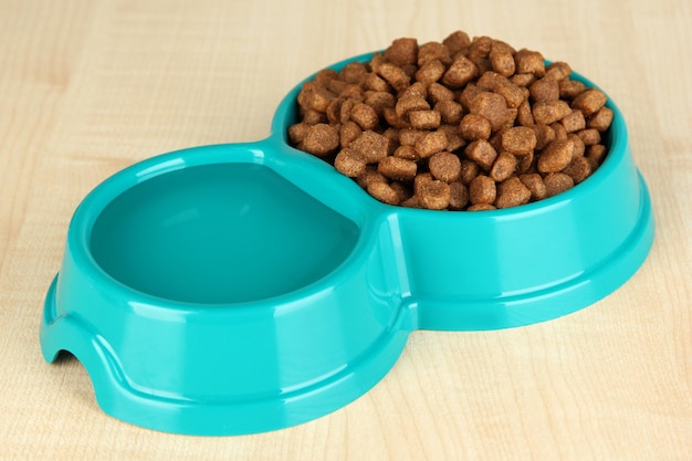 Dry dog food in bowl on wooden background