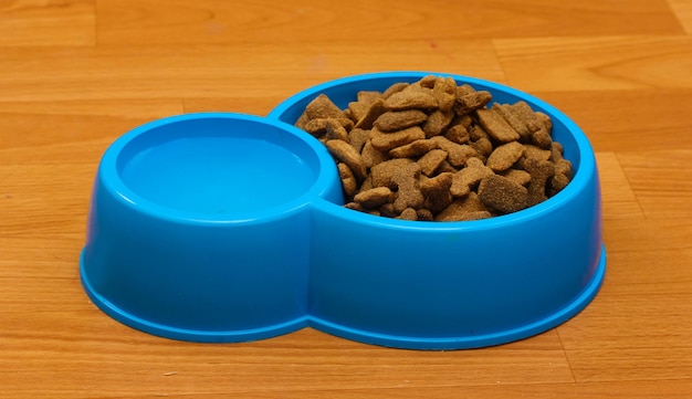 Сухой корм для собак и вода в синей миске на полу