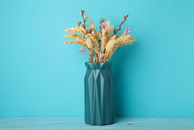 Dry flower in a vase on blue background