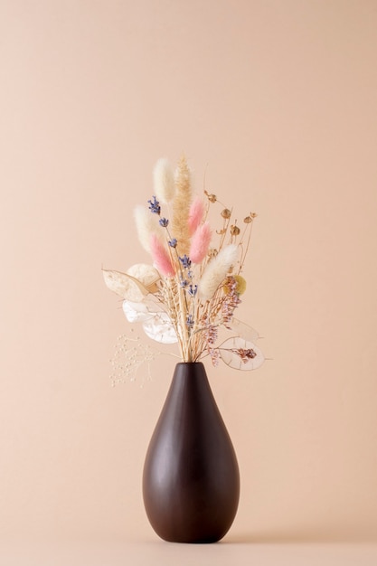 Dry flowers in a brown vase on a light pastel background.