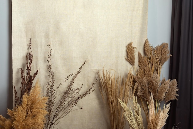 Dry flowers grass and reeds on burlap background Selective focus Space for text Mockup